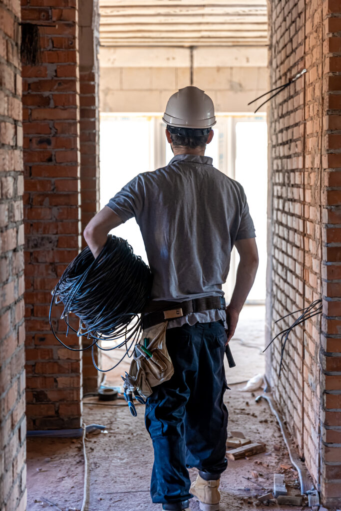 An electrician contractor examines a blueprint at a construction site.